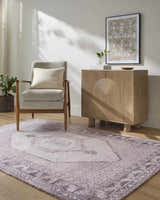 Living room scene with a traditional Wayde Area Rug in dusty rose, gray chair, and light wood cabinet. Roomscene-Rectangle