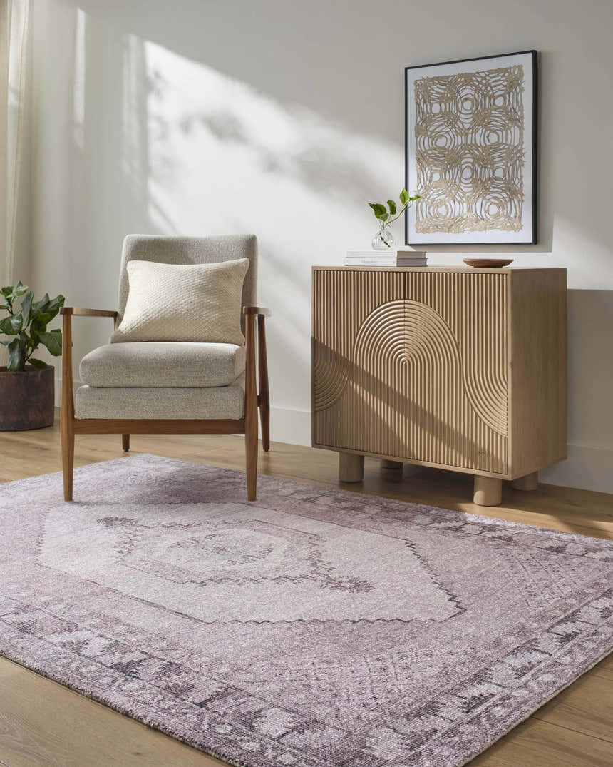 Living room scene with a traditional Wayde Area Rug in dusty rose, gray chair, and light wood cabinet. Roomscene-Rectangle