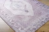 Close up of the Wayde Area Rug, a hand-tufted rug in dusty rose, lavender, and mauve with a traditional farmhouse design. Corner