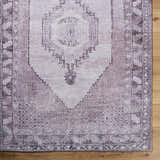 Close up of the Wayde Area Rug. Traditional rug with dusty rose, lavender, and mauve hues on a wood floor. Corner