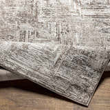 Close-up of the Kutloanong Area Rug showing its charcoal, gray, and ivory abstract pattern and soft texture. Fold