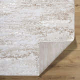 Close-up of Arenda Tan Area Rug showing cream and tan abstract pattern and texture on wooden floor. Fold