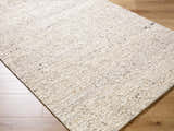 Close-up of the hand-tufted Winta Beige Wool Area Rug showing its cream color, subtle pattern, and soft, textured wool. Corner