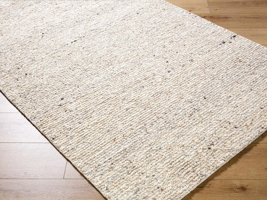 Close-up of the hand-tufted Winta Beige Wool Area Rug showing its cream color, subtle pattern, and soft, textured wool. Corner
