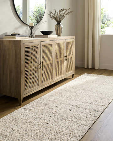 Living room scene with a Winta Beige Wool Area Rug runner, light wood floors, and a rattan cabinet. Roomscene-Runner