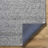 Close-up of the hand-tufted Winta Charcoal Wool Area Rug showing its ash, gray, and silver gray tones and textured wool design. Fold