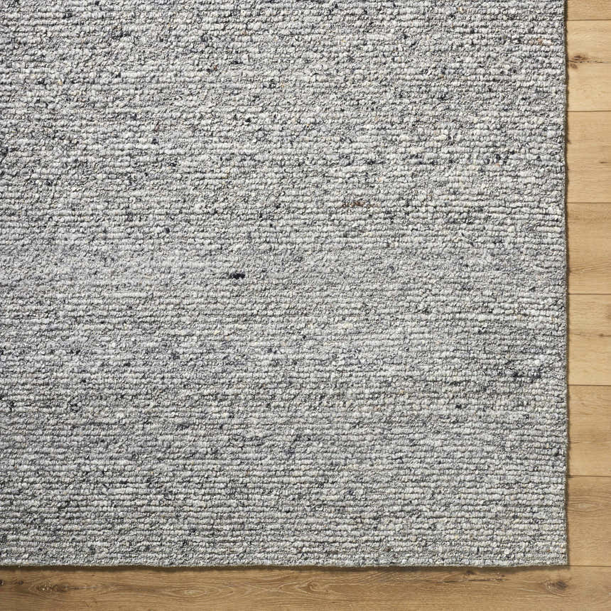 Close-up of the hand-tufted Winta Charcoal Wool Area Rug showing ash, gray, and silver gray tones and textured wool design. Corner