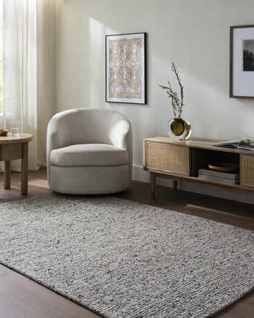 Living room scene with a Winta Charcoal Wool Area Rug, gray chair, and wood media console. Roomscene-Rectangle