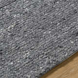Close up of the hand-tufted Winta Black Wool Area Rug, showing gray tones and textured wool fibers. Texture