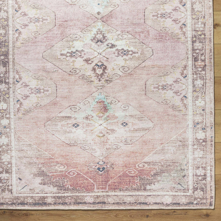 Close up of the Ussun Washable Area Rug. Traditional design in beige, dusty pink, and brown on a wood floor. Corner