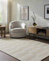 Living room scene with beige Argyro Area Rug, ivory chair, and sandstone-toned furniture. Warm, transitional style. Roomscene-Rectangle