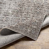 Close-up of the Lugo Luxe Area Rug showing its traditional oriental pattern and charcoal, ivory, and light gray colors. Fold