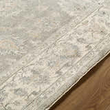 Close-up of the Alinae Area Rug showing its cream, tan, and slate blue traditional floral pattern and soft texture. Texture