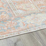 Close-up of the Rust Maayon Washable Rug showing its brick red, blue, and light olive traditional pattern and woven texture. Corner