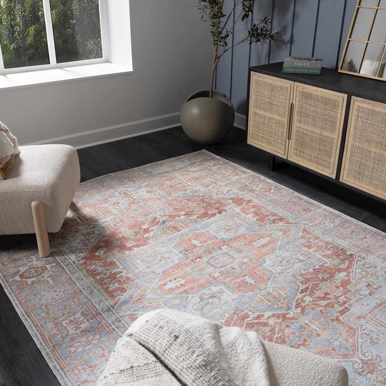 Living room scene with a Rust Maayon Washable Rug, cream chair, and wood cabinet. The rug has a vintage-inspired pattern. Roomscene-Rectangle
