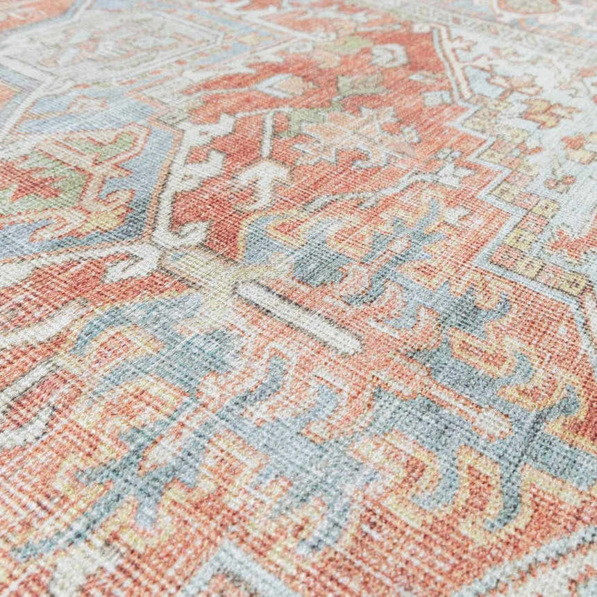 Close-up of the Rust Maayon Washable Rug, featuring a traditional design in brick red, brown, and denim blue tones. Texture