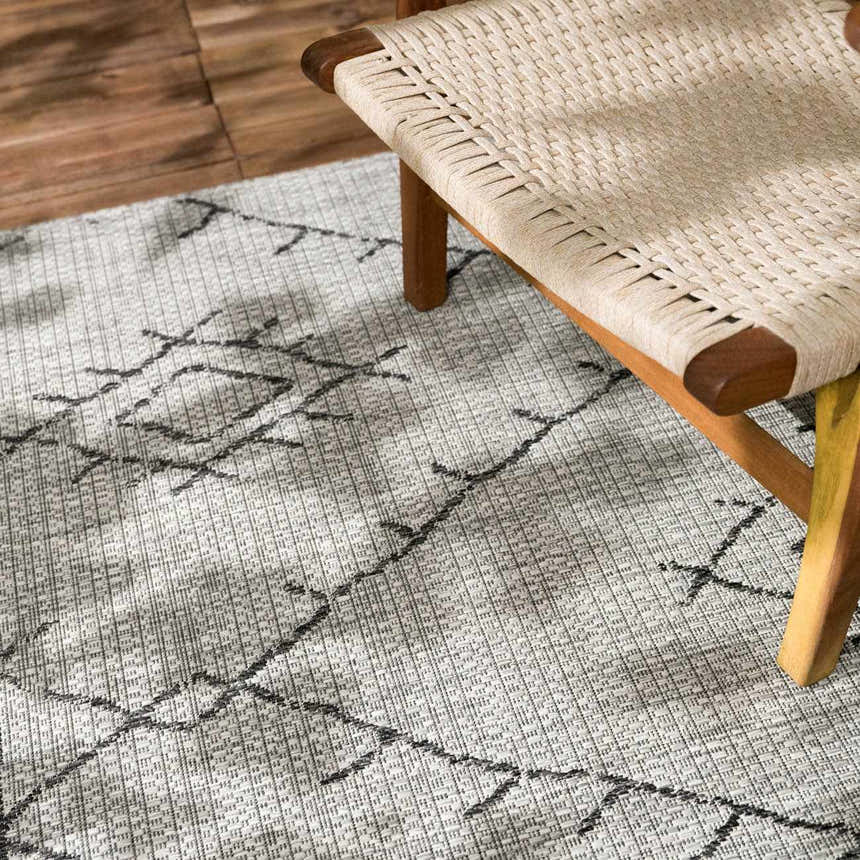 Close-up of the Marwood Nordic Performance Rug showing its black geometric pattern and woven texture next to a chair. Styleshot
