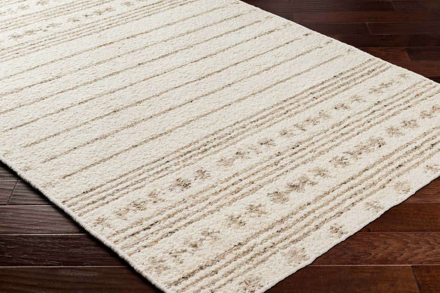 Close-up of the hand woven Matawan Premium Wool Rug in cream with brown stripes on dark wood floors. Corner
