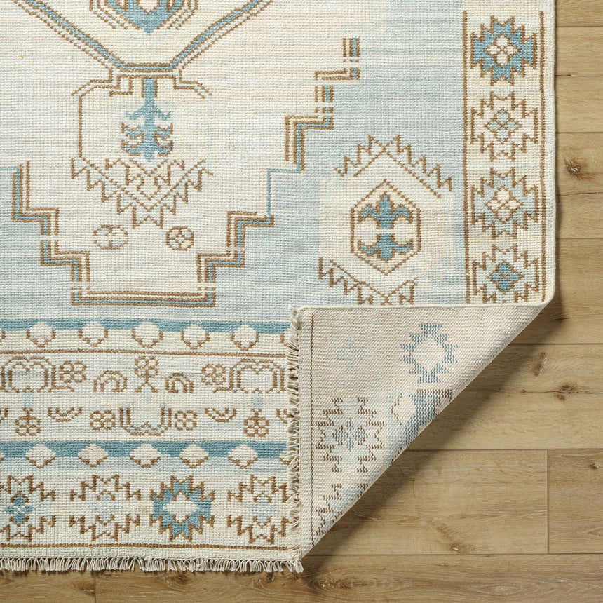 Close-up of McColl Hand Knotted Wool Blend Rug showing cream, brown, and teal geometric pattern and hand knotted construction. Fold