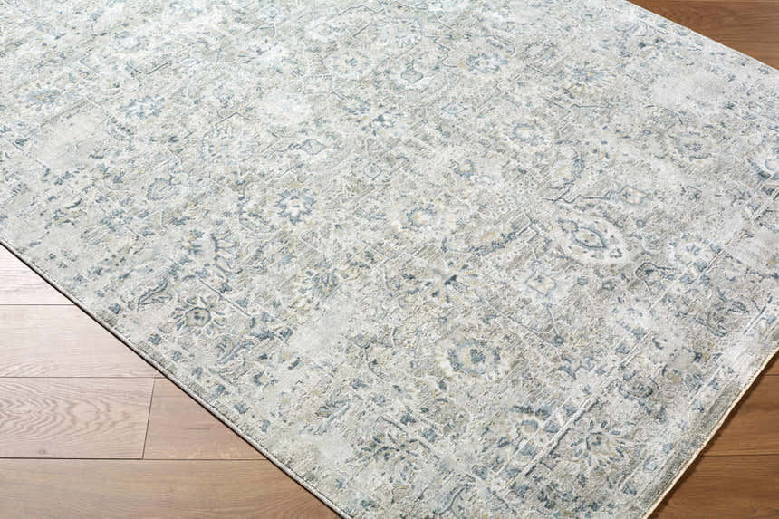 Close-up of the Melianna Gray Blue Thick Luxe Boutique Rug showing its traditional floral pattern and soft blue, cream, and gray colors. Corner