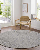 Light-filled room with round Melianna Gray Blue rug under a woven chair. Farmhouse style with wood floors. Roomscene-Round