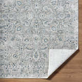 Close-up of the Melianna Gray Blue Luxe rug showing its traditional floral pattern and soft texture on a wood floor. Fold