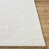 Close-up of the plush, white Alysha Area Rug showing its shag texture and machine-woven construction on wood floor. Front
