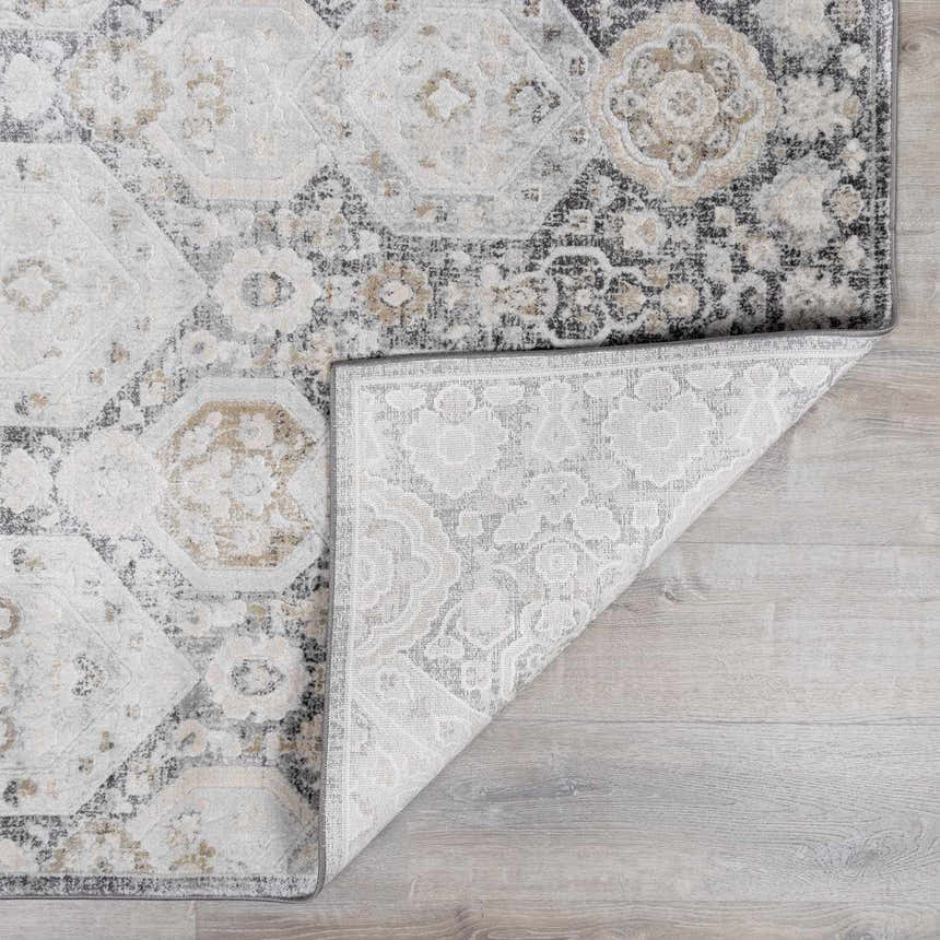 Close-up of the Minoa Area Rug featuring a beige, black, and gray bohemian pattern with a folded corner showing the rug's backing. Fold