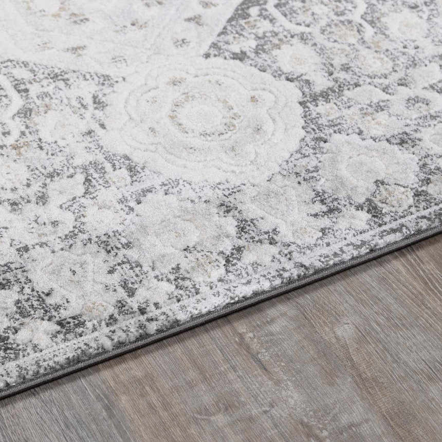 Close-up of the Minoa Area Rug showing its off-white floral pattern and gray accents on a light wood floor. Corner