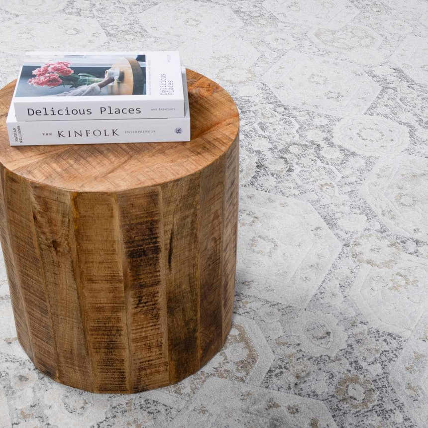 Close-up of the beige and gray Minoa Area Rug with a wood side table and books. Styleshot