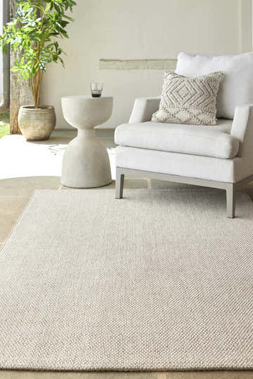 Neutral patio scene with ivory Midha Area Rug, modern chair, side table, and potted plant. Roomscene-Rectangle