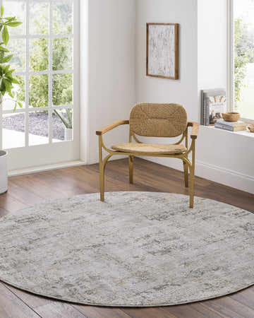 Bright room scene with a round Meral Thick Luxe Boutique Rug in charcoal, cream, and gray under a woven chair. Roomscene-Round