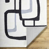 Close-up of the Ulfah Area Rug, a hand-tufted wool rug with a modern black and ash geometric design. Fold