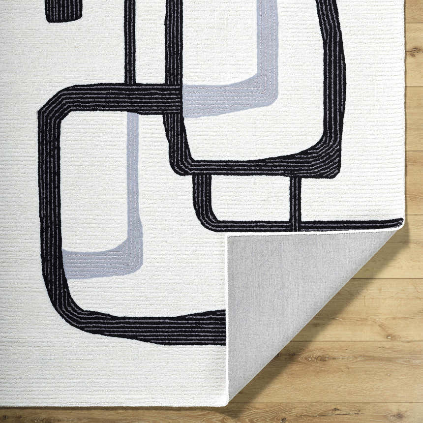 Close-up of the Ulfah Area Rug, a hand-tufted wool rug with a modern black and ash geometric design. Fold