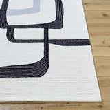 Close-up of the Ulfah Area Rug showing its ash and jet black geometric design and hand-tufted wool texture. Front