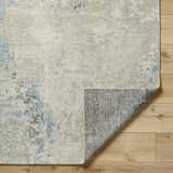 Close up of the Marco Handmade Wool Rug in cream, charcoal, and denim on light wood floors. Fold