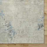 Close-up of the Marco Handmade Wool Rug. Features charcoal, cream, denim, and beige tones with a subtle contemporary pattern. Corner