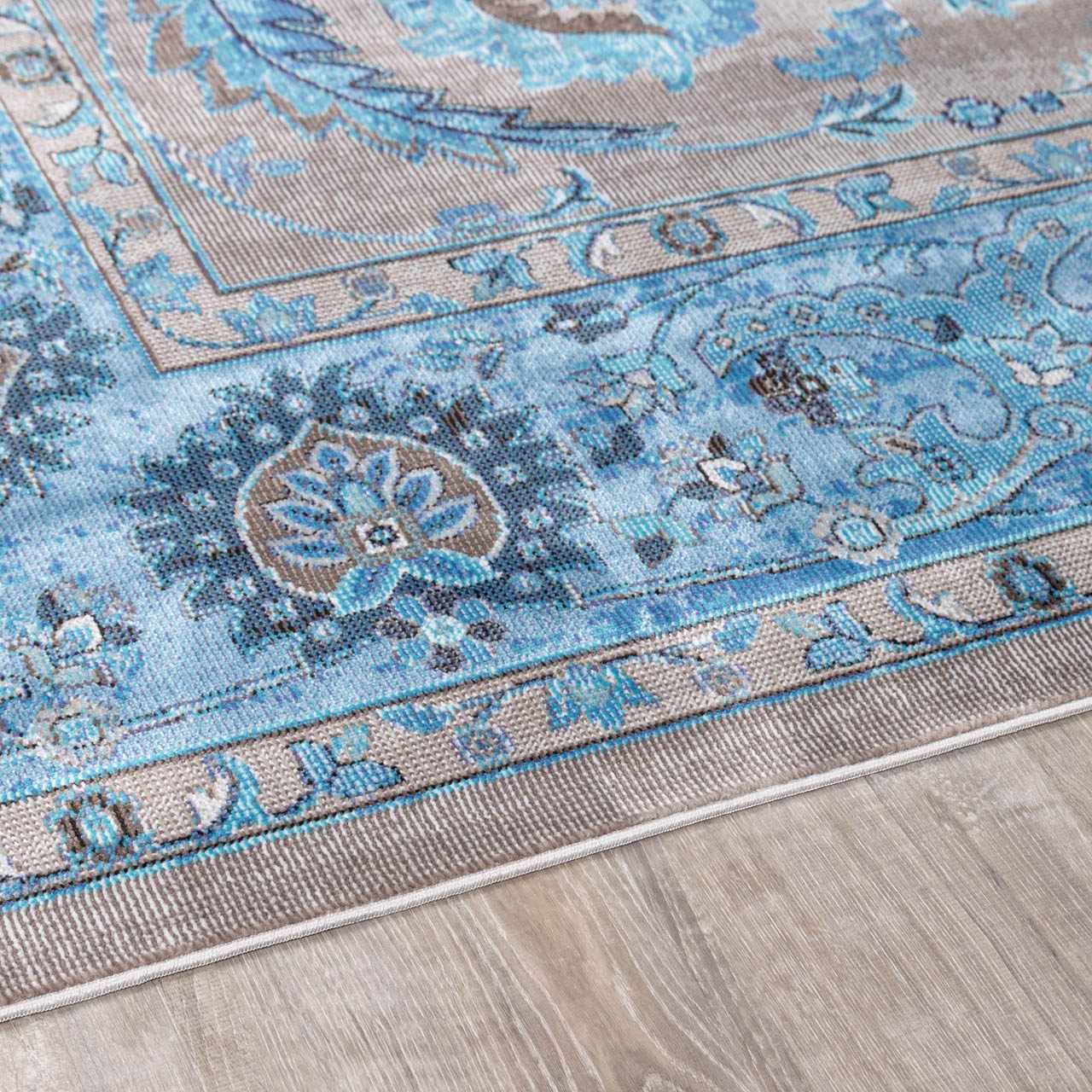 Close-up of the Mardina Turquoise Area Rug showing its beige and blue traditional vintage pattern and machine-woven texture. Pile