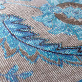 Close up of Mardina Turquoise rug showing beige ground with detailed turquoise floral pattern. Texture