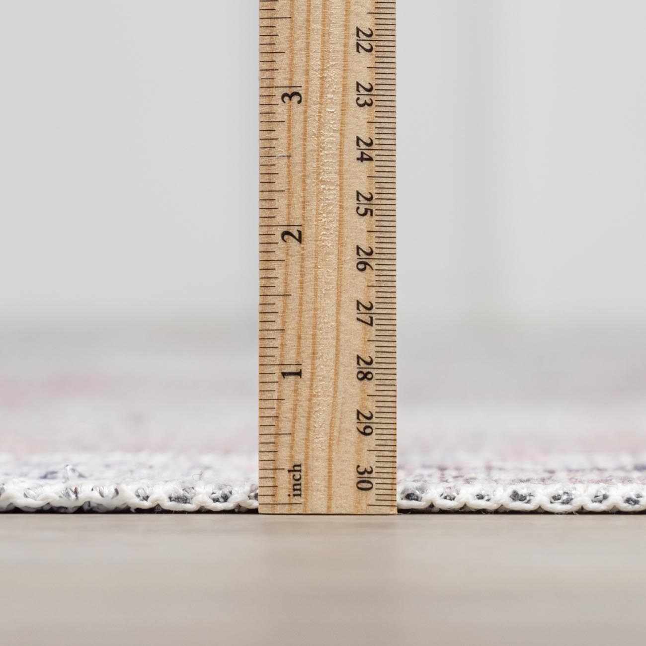 Close-up of the Moora Washable Area Rug showing rug thickness with a ruler. Chenille-Polyester material. Pile