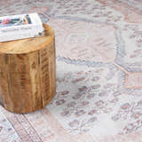 Close-up of the Moora Washable Area Rug showing its traditional, floral pattern and soft aqua, blush, and brown colors. Styleshot