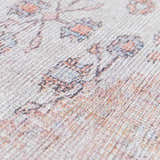 Close-up of the Moora Washable Area Rug showing its chenille texture and floral pattern in aqua, blush, and coral tones. Texture