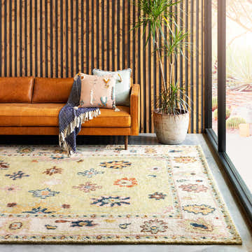 Living room scene with a leather sofa and the Naas Premium Rug in brick red, cream, and blue. Roomscene-Rectangle