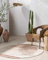 Minimalist room with a round Nabil Cream Area Rug, wicker chair, terracotta pots, and cactus. Roomscene-Round