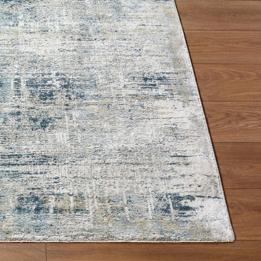 Close-up of the Neron Thick Luxe Abstract Rug showing blue, cream, and charcoal abstract design on wood floor. Front