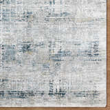 Close-up of the Neron Thick Luxe Abstract Rug. Features a blue, charcoal, cream, and gray Southwestern-style pattern. Corner