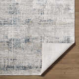 Close-up of the Neron Thick Luxe Abstract Rug. Features blue, charcoal, cream, and mustard hues in an abstract pattern. Fold