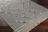 Close-up of the Needville Gray High-Low Rug, showcasing its geometric design, fringe detail, and hand-woven texture on a wood floor. Corner