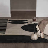 Living room detail with black and cream Brooklyn Modern hand tufted wool area rug, side table, and blanket. Styleshot