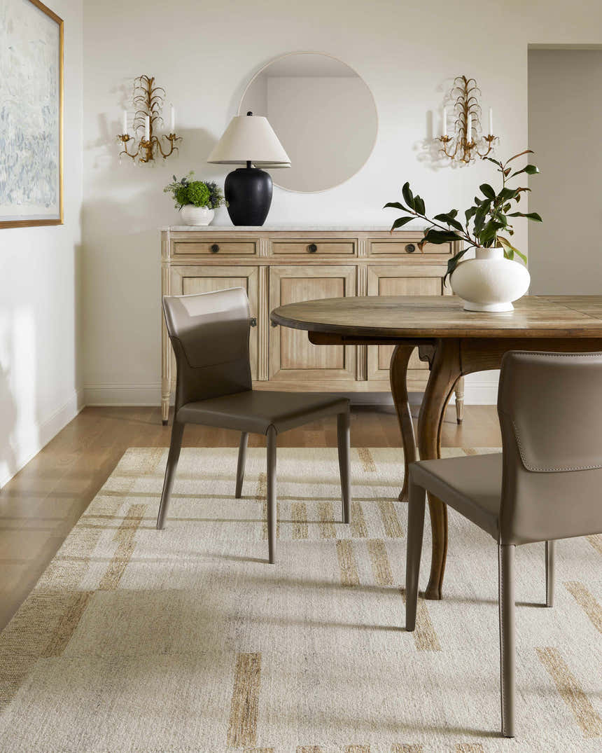 Dining room with a Max Handmade Becki Owens x LIVABLISS rug in cream and tan, under a wooden table and taupe chairs. Roomscene-Rectangle